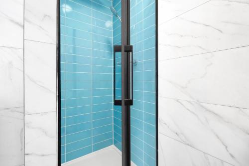伦敦Waterside 4 Bed Apartment的浴室设有玻璃淋浴间,铺有蓝色瓷砖