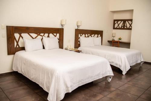 马德罗城Hotel Tres Soles的配有白色床单的客房内的两张床
