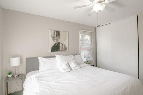 莫比尔Enchanting Forestwood Retreat的白色卧室配有白色床和吊扇