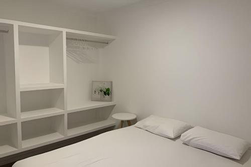 福塔莱萨Hosts BR - Apartamentos funcionais的一间白色卧室,配有床和书架