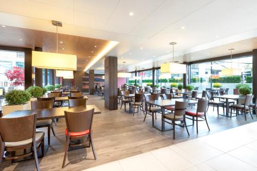 吕姆朗Holiday Inn Express Zürich Airport, an IHG Hotel的餐厅设有桌椅和窗户。