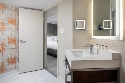 多伦多多伦多机场皇冠假日酒店的一间带水槽和镜子的浴室以及一张床
