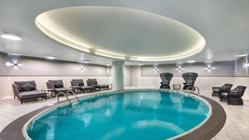 多伦多多伦多机场皇冠假日酒店的酒店大堂的游泳池,配有桌椅