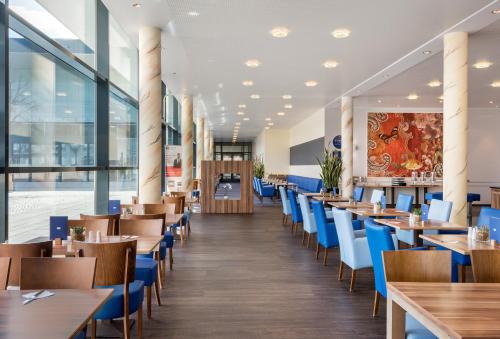 辛根辛根快捷假日酒店的用餐室配有木桌和蓝色椅子