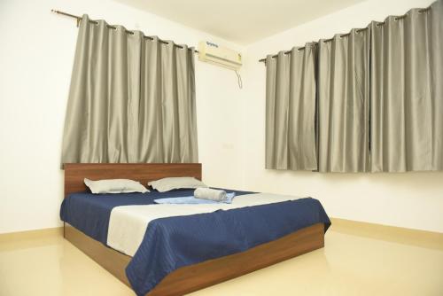 帕纳吉Sai Homestay Panaji 2 BHK and Studio Apartment的一间卧室配有一张带蓝色床单和窗帘的床