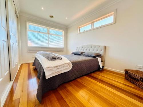 墨尔本Townhouse Near The World’s Coolest High st in 2024的一间卧室配有一张铺有木地板的床和两个窗户。