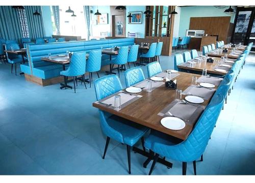 贾姆讷格尔Nulife Resort的一间带长桌和蓝色椅子的用餐室