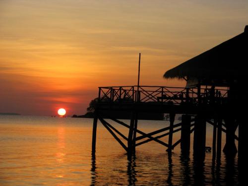 特鲁克巴库卢拉冒险度假村的水面上的码头,背景是日落