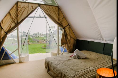 贝都古Popitan Garden Campground & Glamping Bedugul的一个带大窗户的帐篷内一间卧室,配有一张床