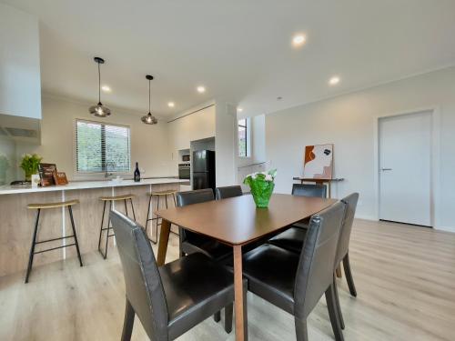 奥克兰Glendowie Brand-new comfortable 3 & 4-bedroom Houses的用餐室以及带木桌和椅子的厨房