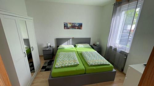 比伯斯海姆Ferienwohnung -Isola Madre的一间卧室设有两张带绿床单的床和窗户。