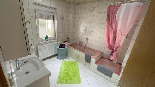 比伯斯海姆Ferienwohnung -Isola Madre的浴室配有粉色浴缸、水槽和浴缸。