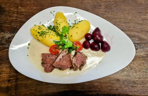 LeipePension & Biergarten Spreewaldhof Leipe的桌上一盘带肉和水果的食物