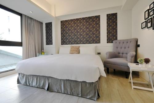台中市悅柏行旅 逢甲館 YABO Inn的一间卧室配有一张大床和一把椅子