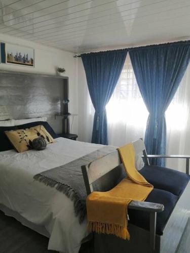 奇帕塔Ticia Apartment的一间卧室配有一张带蓝色窗帘的床和一把椅子
