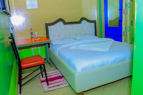 KisiiMalibu Lounge Bar & Restaurant的卧室配有1张床、1张桌子和1把椅子