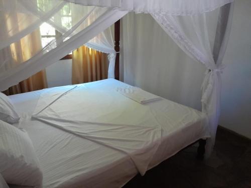 马林迪Lion Garden Villa 7的卧室内的白色床和天蓬