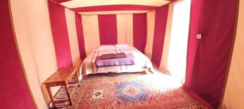 姆哈米德Chigaga Desert Camp的一间红色条纹间内带一张床的卧室
