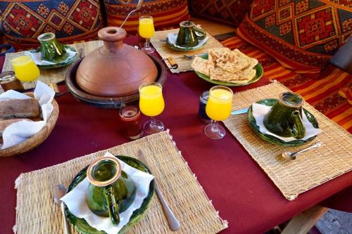 姆哈米德Chigaga Desert Camp的餐桌,带食物盘和橙汁杯