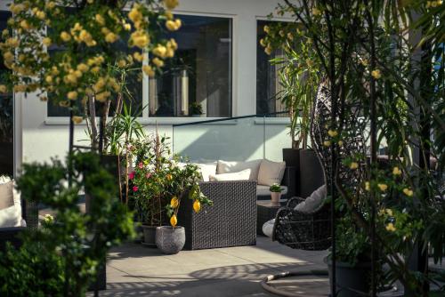 梅拉诺拉德纳酒店的庭院里种有盆栽植物,配有沙发和椅子