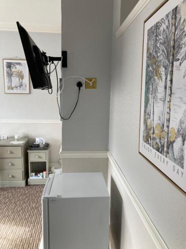 韦茅斯Braemar的客房设有书桌和墙上的电视