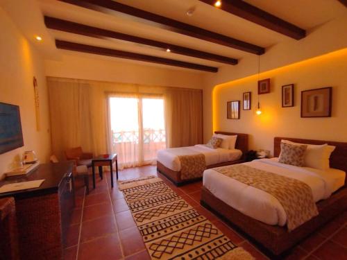 考拉亚湾Amarina Jannah Resort & Aqua Park的一间卧室设有两张床、一张桌子和一个窗口。