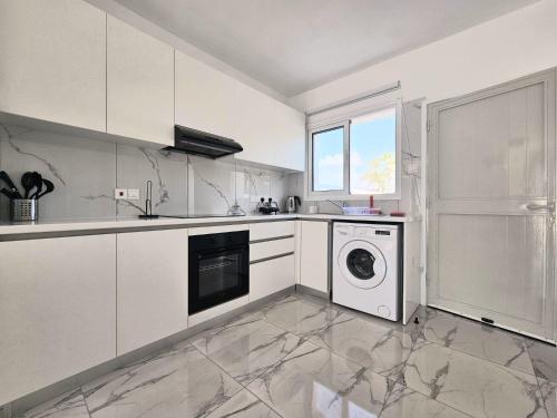 帕福斯2BD Garden Apartment的厨房配有白色橱柜、洗衣机和烘干机