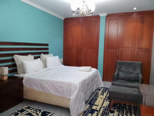 MumbwaALIJAY APARTMENTS的一间卧室配有一张大床和一把椅子