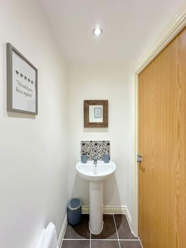 DinningtonLuxury 3 Bedroom House With FREE Parking的一间带白色水槽和木门的浴室