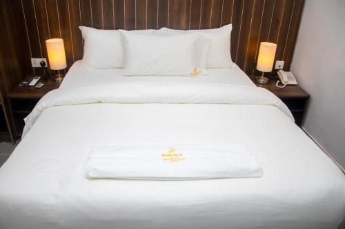 拉各斯Baseville Hotel的一张大白床,位于酒店带两盏灯的房间