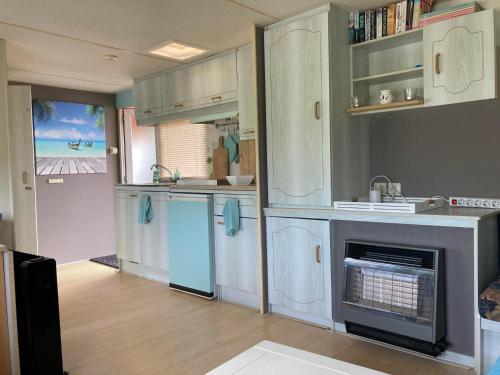 OudehaskeAqua Beach House的厨房配有白色橱柜和壁炉