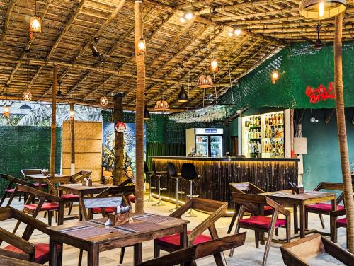 曼德姆Seaside Serenity Resort的一间带木桌椅的餐厅和一间酒吧