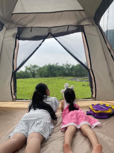Kim BôiCamping Suối Cái的两个女孩躺在帐篷里,望着窗外