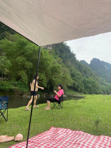 Kim BôiCamping Suối Cái的两个人坐在河边帐篷下的椅子上
