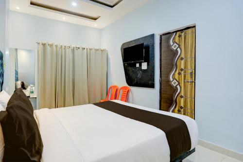 瓦拉纳西OYO Flagship SHIVA VALLEY HOTEL的卧室配有一张床,墙上配有电视。