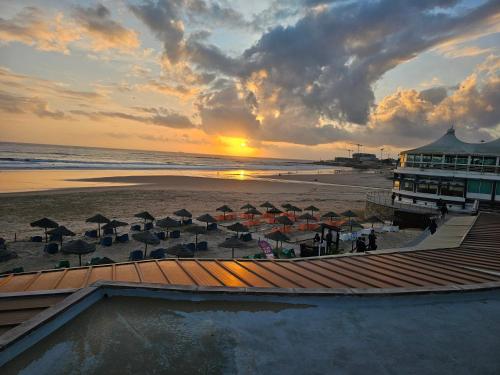 卡斯卡伊斯Peers Guest House的海滩上的日落,太阳伞和海洋
