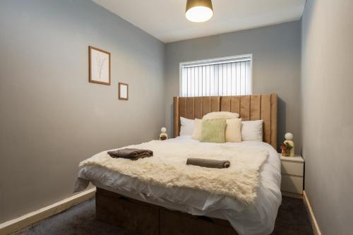罗瑟勒姆Lovely Getaway Apartment: Two-Bedroom in Rotherham的一间卧室配有一张大床和木制床头板