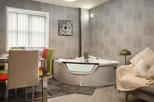 罗瑟勒姆Lovely Getaway Apartment: Two-Bedroom in Rotherham的带浴缸、桌子和沙发的浴室