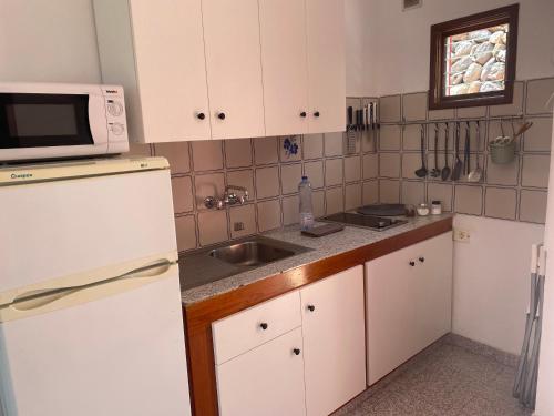 埃尔米瓜普拉亚公寓的厨房配有白色橱柜、水槽和微波炉