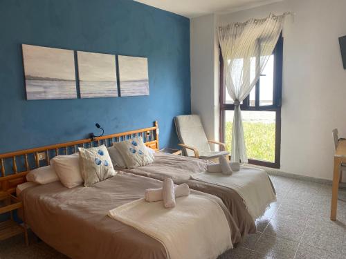 埃尔米瓜普拉亚公寓的一间卧室设有两张带蓝色墙壁和窗户的床。