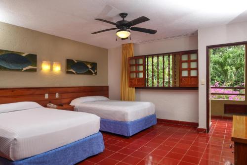科苏梅尔殖民套房酒店的一间卧室配有两张床和吊扇