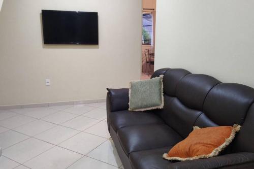 CaratingaAcomodação paraju-apartamento em caratinga的客厅设有一张黑色皮沙发,配有电视