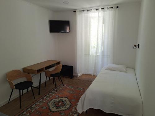 辛特拉Penaferrim Sintra Rooms的一间卧室配有一张床、一张书桌和一台电视