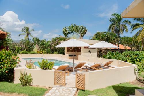 拉斯加勒拉斯Villa Diana的房屋旁的游泳池配有椅子和遮阳伞
