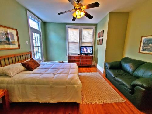 匹兹堡Point Breeze Guest House的一间卧室配有一张床、一张沙发和吊扇。