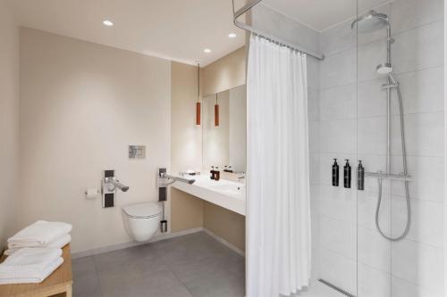 哥本哈根Residence Inn by Marriott Copenhagen Nordhavn的带淋浴和盥洗盆的白色浴室