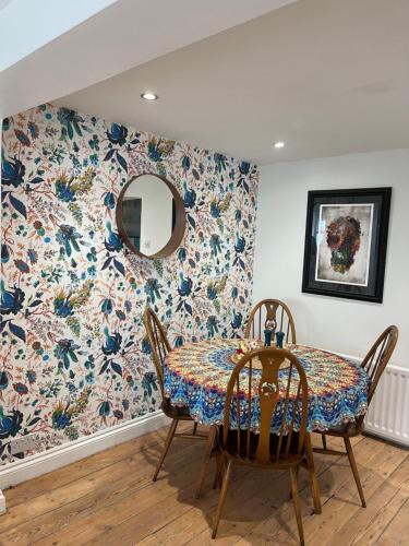 布莱顿霍夫North Laine Sunny Cottage的用餐室配有带花卉壁纸的桌子