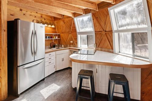 拉派恩Dome Home的厨房配有冰箱和2个吧台凳