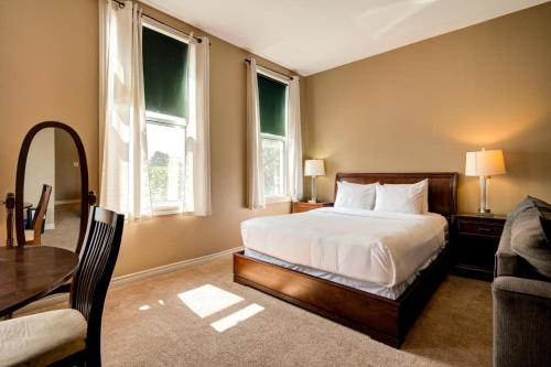 斯特拉福德The Avonlea Inn的一间卧室配有一张床、一张桌子和两个窗户