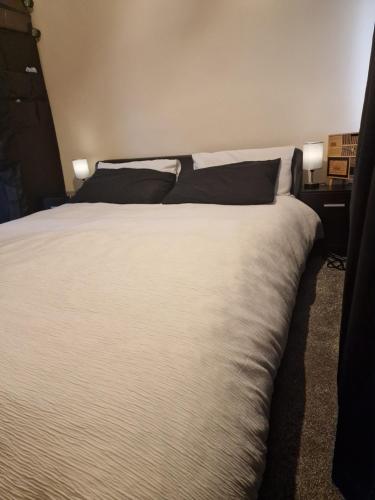 HadleighCosy Hadleigh的卧室内一张带黑色枕头的大型白色床